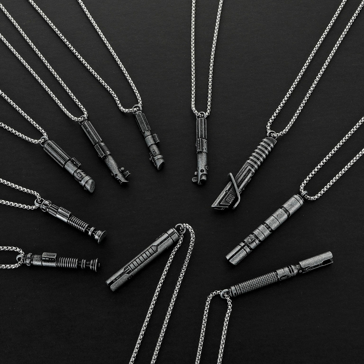 Ten silver-tone miniature saber hilt necklaces arranged on a dark surface